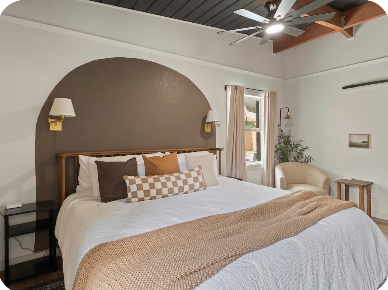 Neutral primary bedroom set with an arched feature wall at the Dallas Creative Connect location.